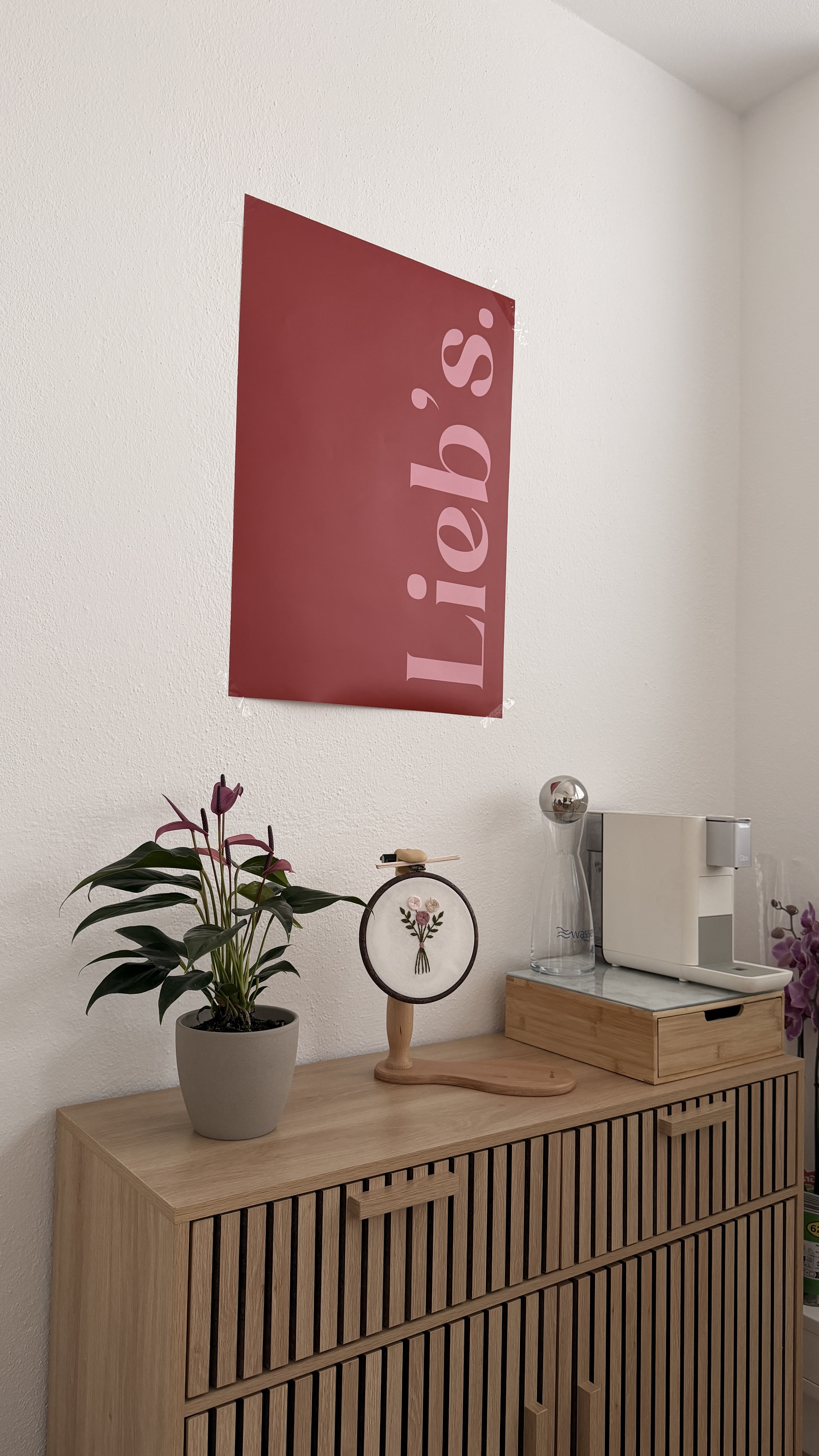 Sideboard mit Lieb's-Poster und Dekoration