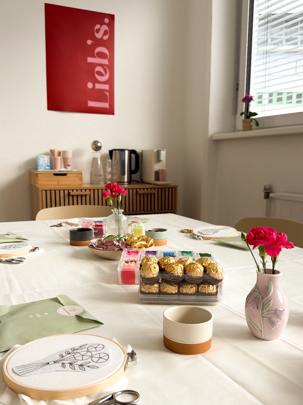 Gedeckter Workshop-Tisch mit Stickereien, Garnen und Blumen